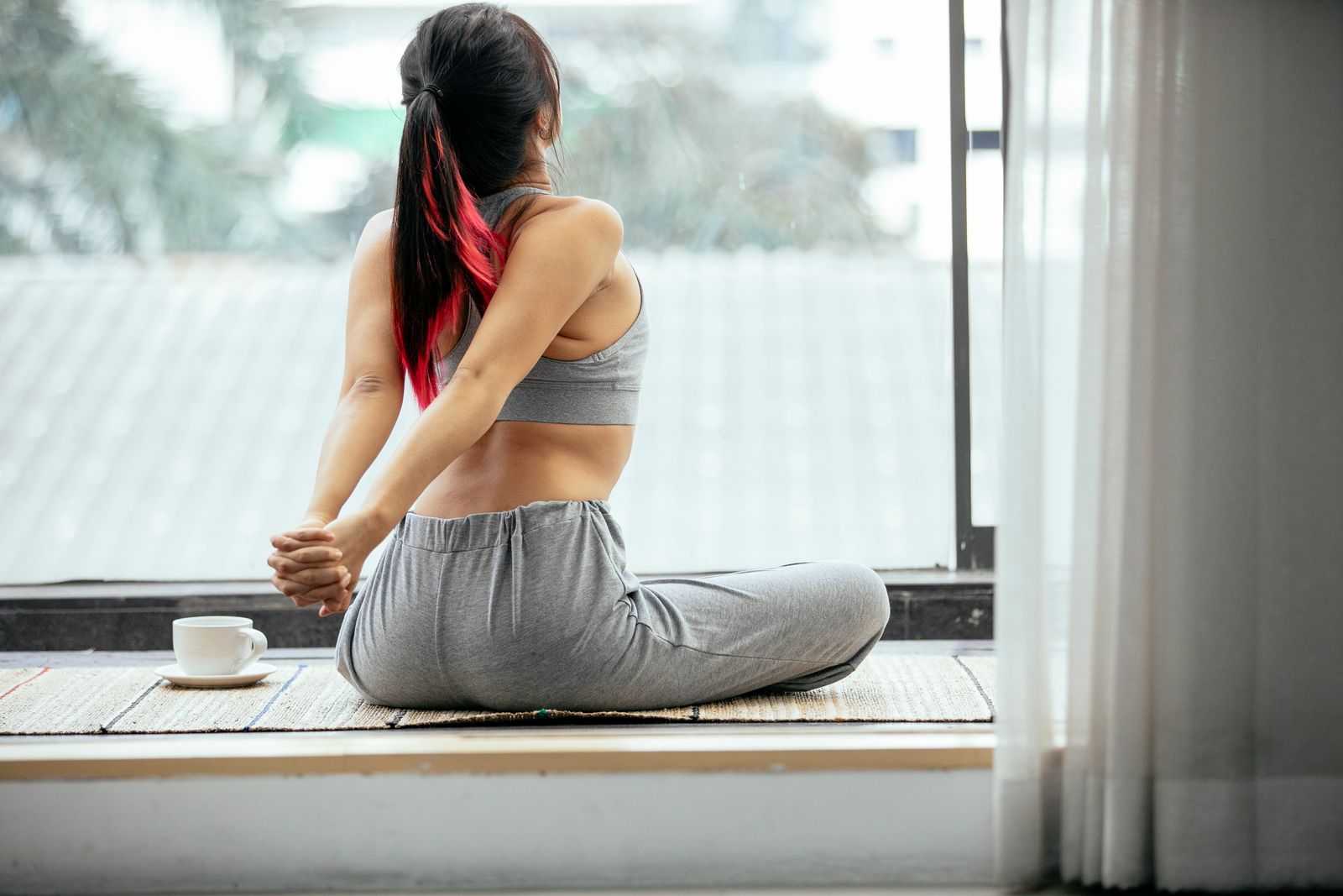 A person stretching gently beside a bright window